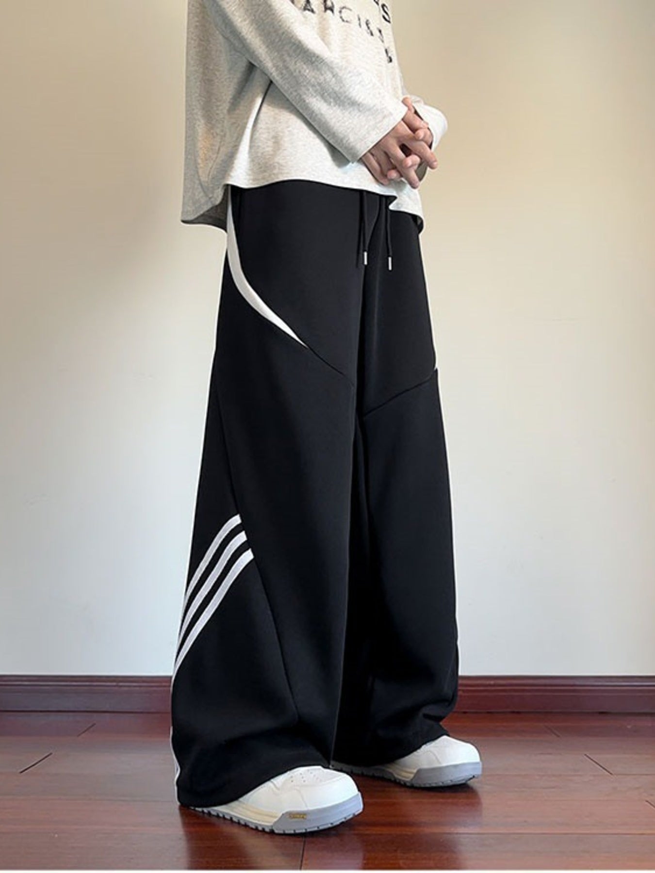 Black wide-leg sweatpants with white stripe details and a drawstring waist.
