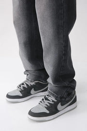 Faded wash baggy jeans in dark denim, styled with sneakers.