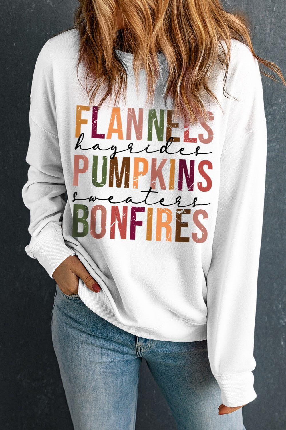 White crewneck sweatshirt with autumnal graphic text: Flannels, Hayrides, Pumpkins, Sweaters, Bonfires.