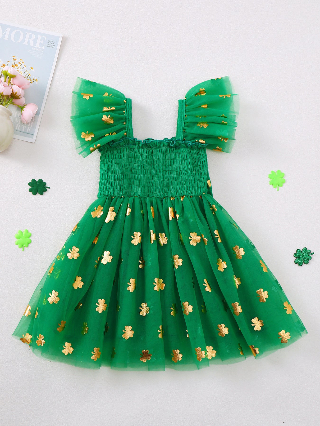 Green tulle baby dress with gold shamrock print, smocked bodice, and flutter sleeves.