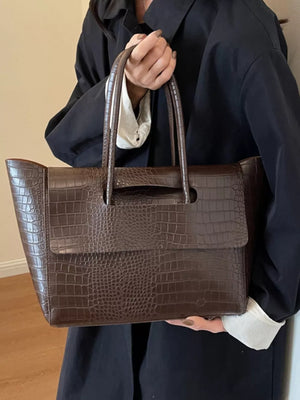 Brown crocodile-embossed medium tote bag with top handles and a flap detail.