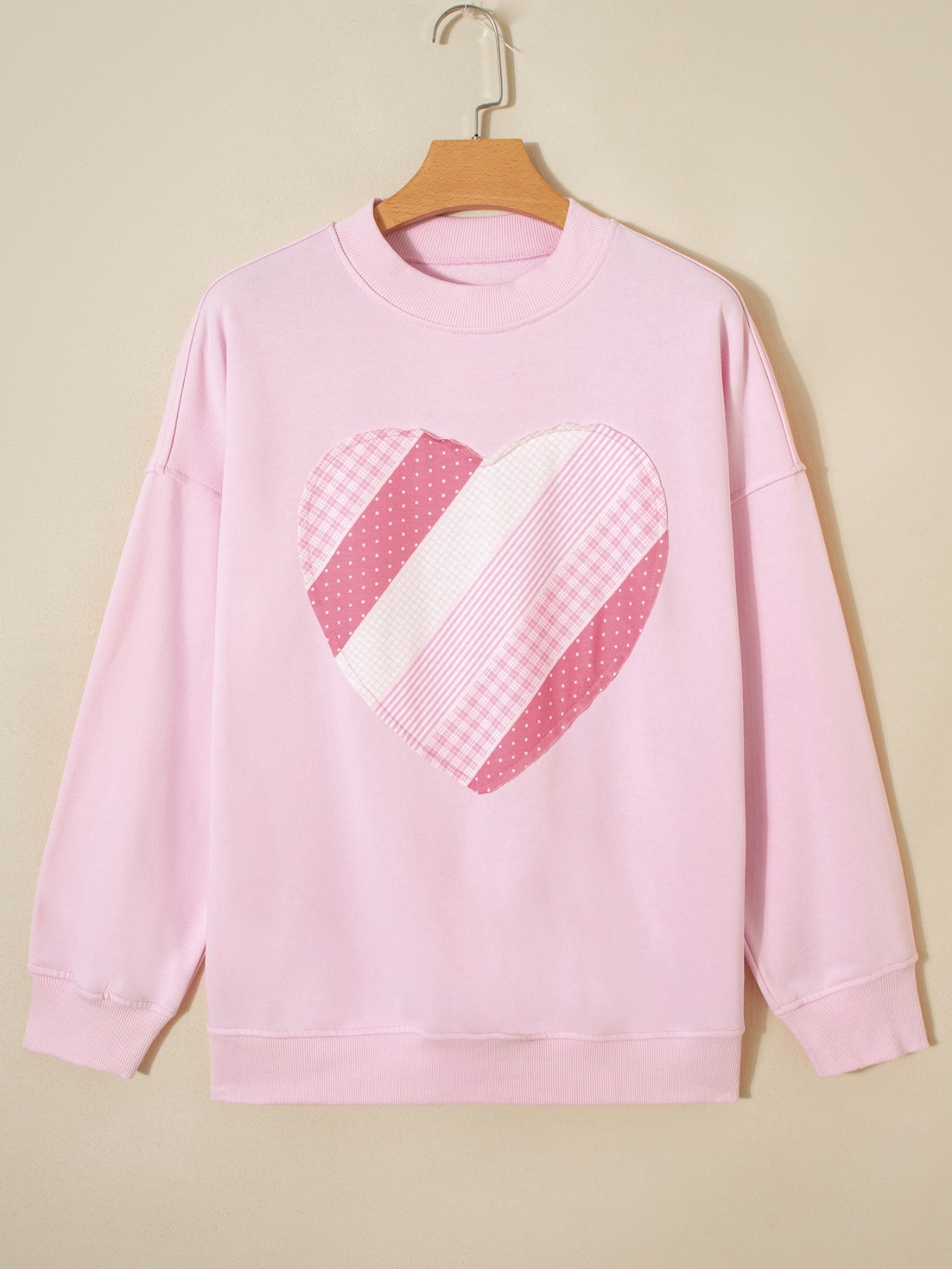 Pink cotton crew neck sweatshirt with a patchwork heart graphic.
