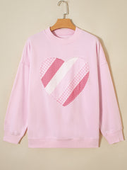 Pink cotton crew neck sweatshirt with a patchwork heart graphic.