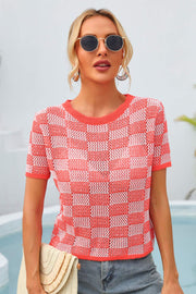 Checkerboard knit crewneck top in orange and white with short sleeves.
