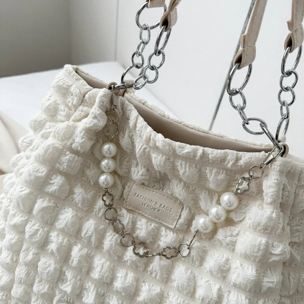 Textured grid pearl chain tote in ivory with chain and pearl detail.