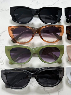 Sculpted cat eye sunglasses in sage green, black, and translucent gray with gradient lenses.