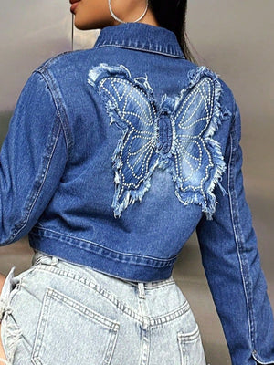 Medium wash denim crop trucker jacket with embroidered butterfly detail and frayed hem.