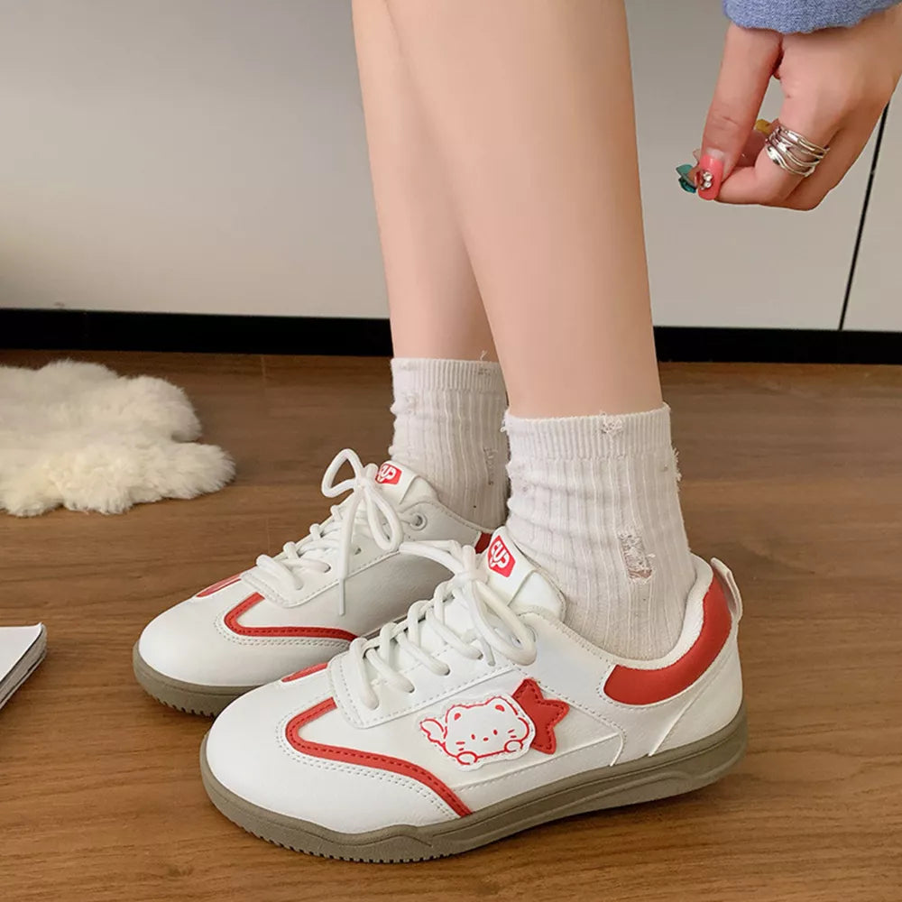 White lace-up sneakers with red trim and a cute cartoon cat accent.