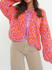 Vibrant leopard print tie-front cardigan in pink and orange with long sleeves and a cropped fit.