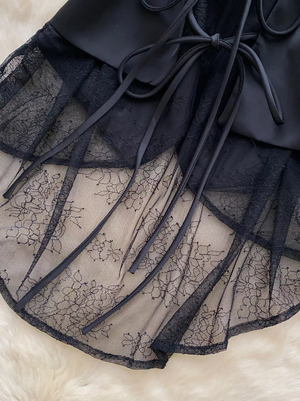 Black lace-embellished button-down vest coat with tie detail and floral lace overlay.