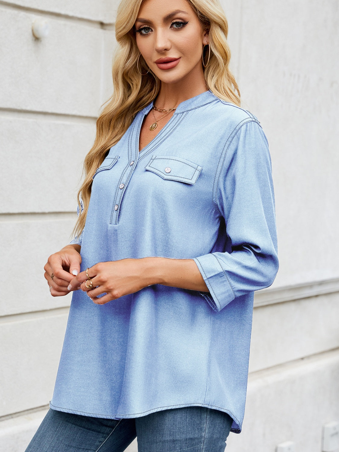 Light blue denim henley blouse with V-neck, button placket, and two chest pockets.