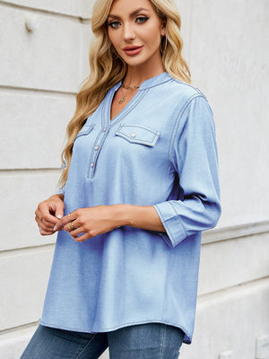 Light blue denim henley blouse with V-neck, button placket, and two chest pockets.