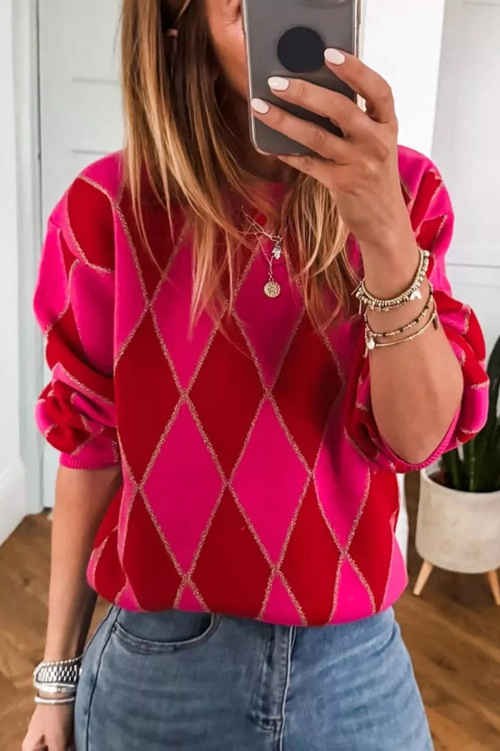 Vibrant argyle knit sweater with puff sleeves in deep rose and red, featuring gold sparkle detail.