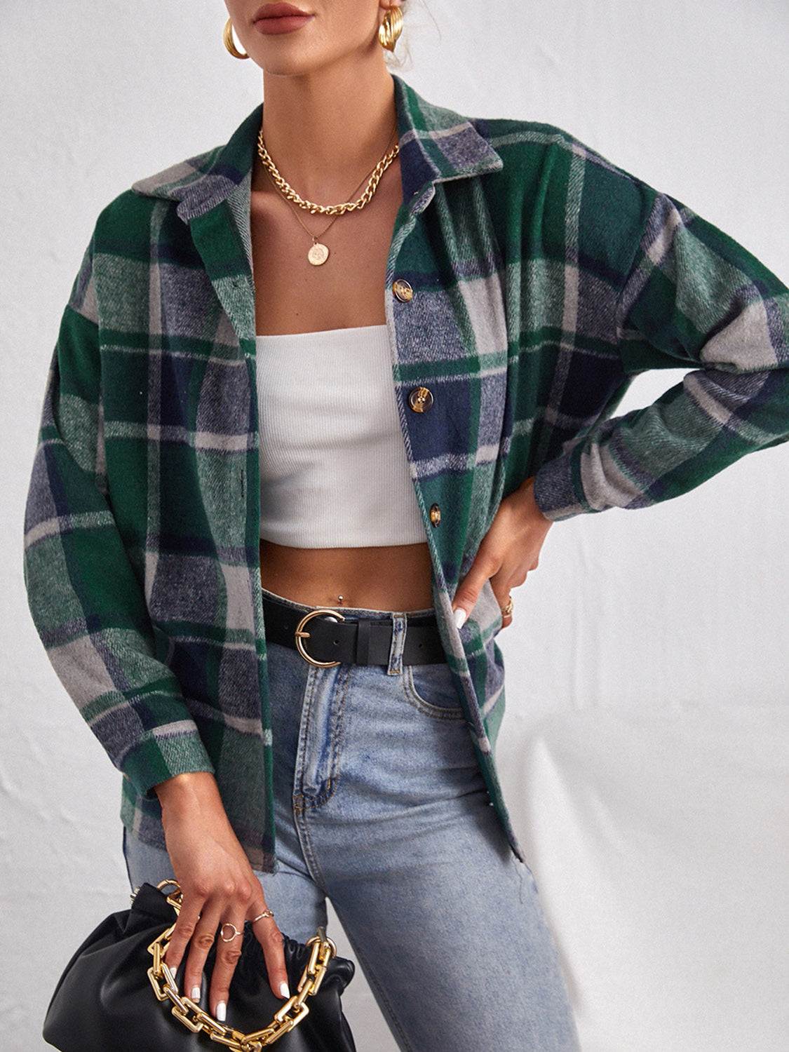 Oversized plaid shacket in dark green with button closure, worn open over a white crop top.