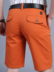 Men's orange chino shorts with back pockets and button detail.