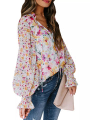 Vibrant floral print blouse with tie detail, long balloon sleeves, and smocked cuffs.