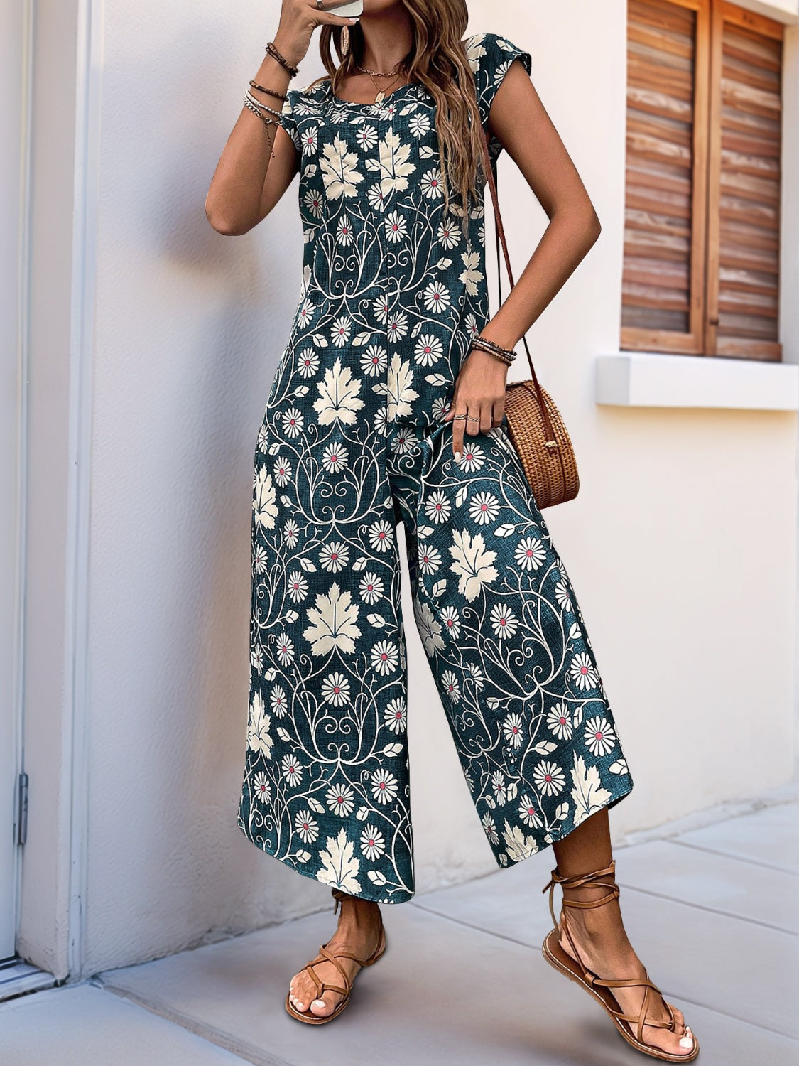 Botanical print culotte jumpsuit in dark green with cap sleeves and a round neckline.
