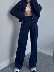 Dark blue zip-up jacket and wide-leg sweatpants with drawstring waist and seam detail.