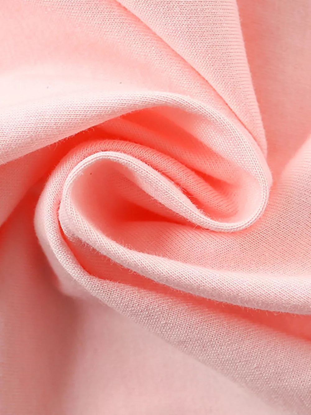 Close-up of apricot cotton fabric with soft folds and visible stitching.