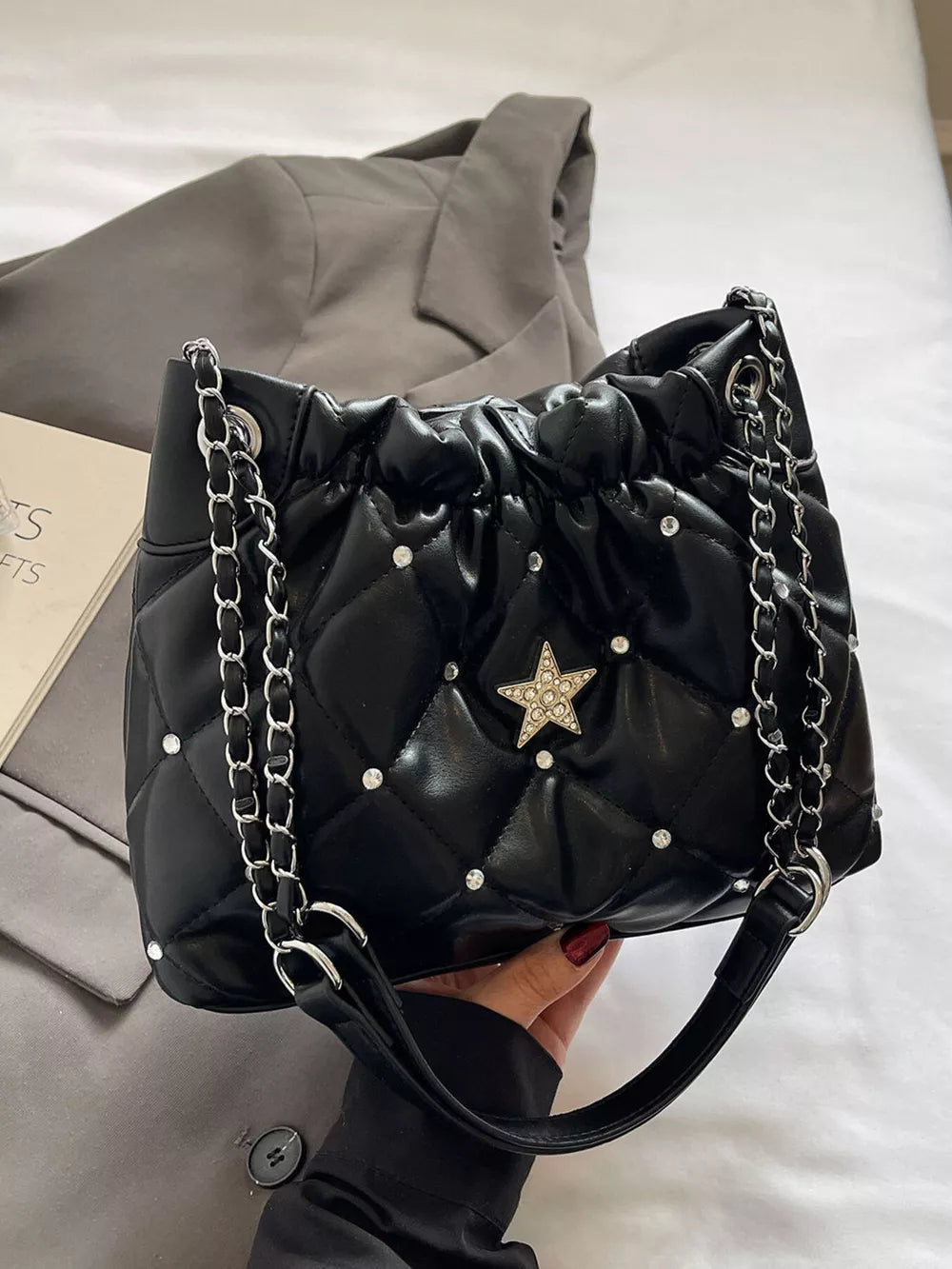 Black quilted shoulder bag with rhinestone star and diamond pattern details.