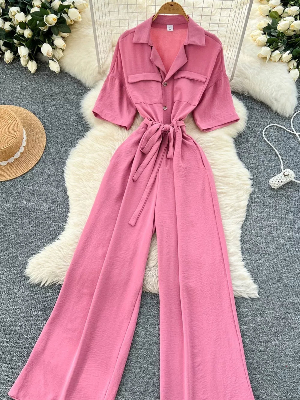 Pink belted wide-leg maternity jumpsuit with pockets and buttoned front.