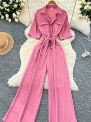 Pink belted wide-leg maternity jumpsuit with pockets and buttoned front.