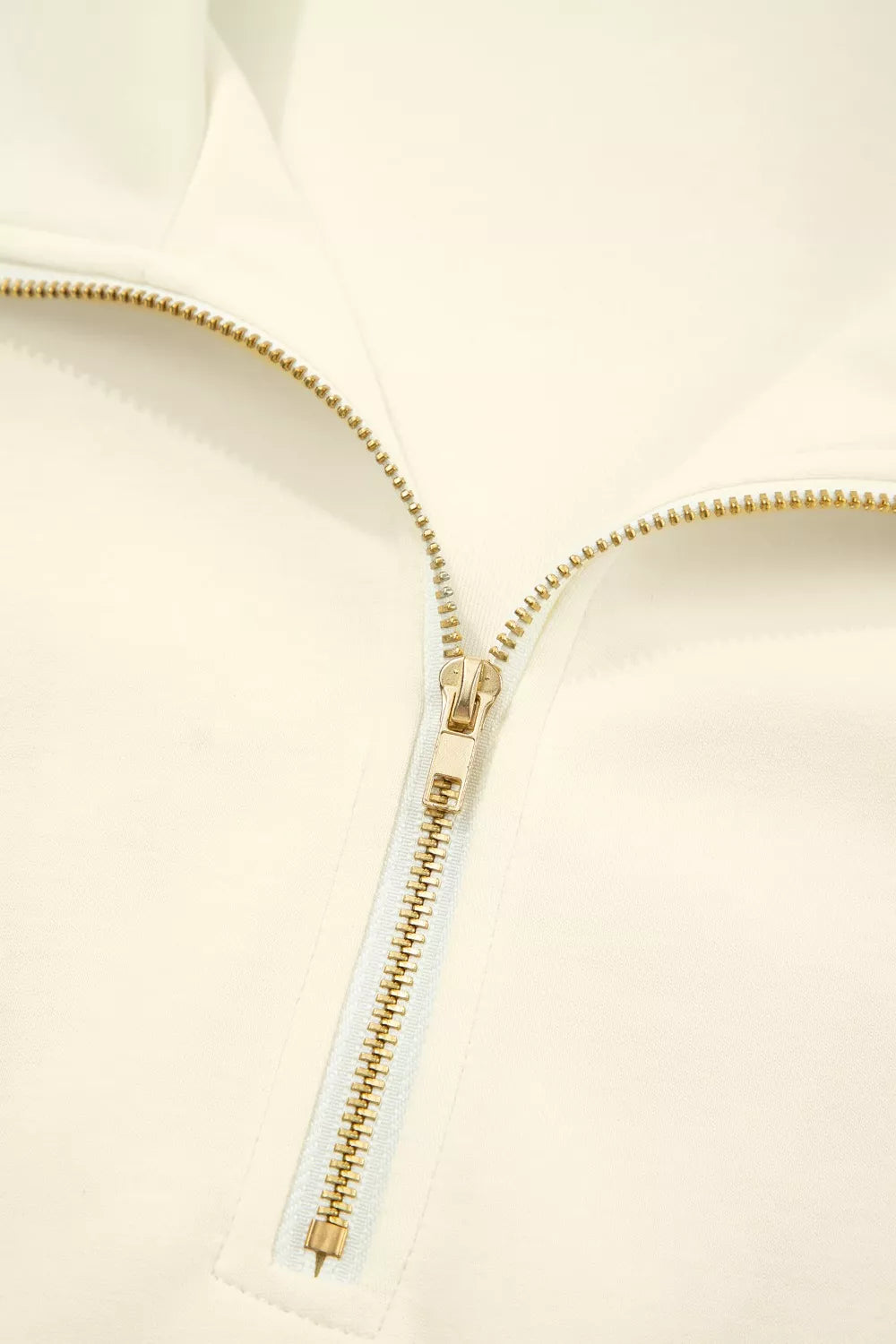 Cream cotton zip blouse with stand-up collar and ruffled detail.