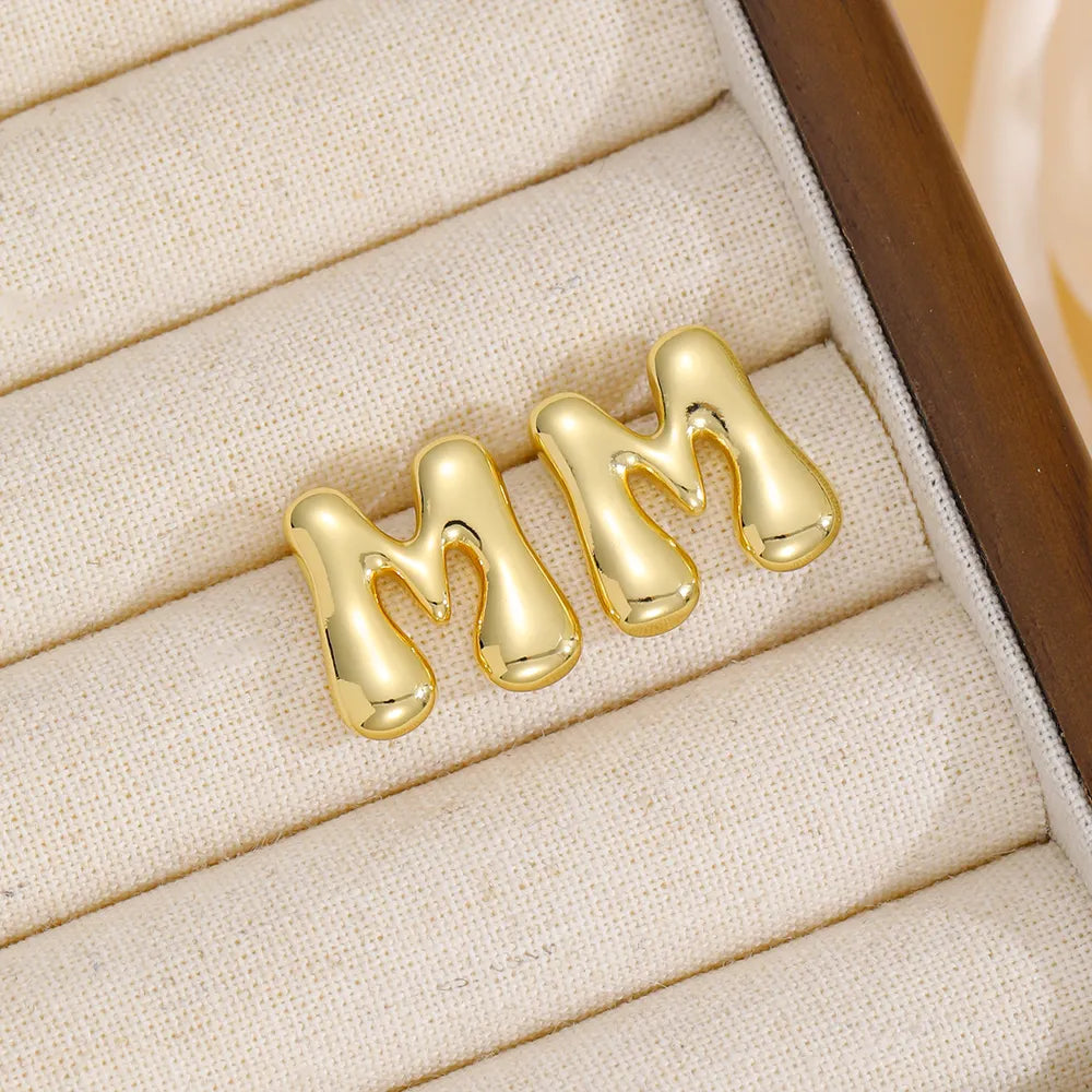 Gold sculptural stud earrings in the shape of the letter M