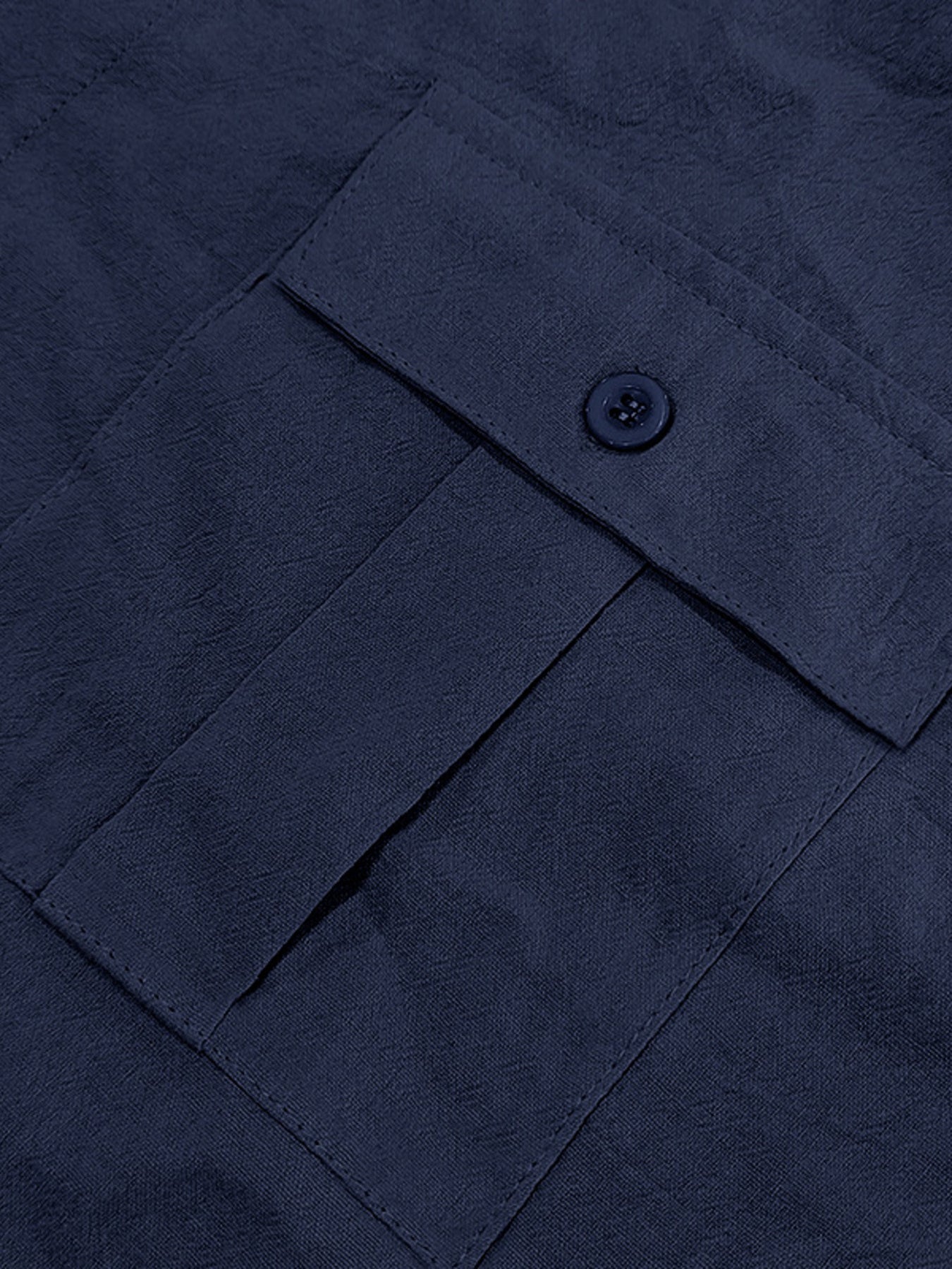 Navy blue button-down shirt detail showing a pocket with a button closure and textured fabric.