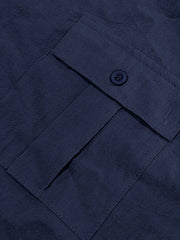Navy blue button-down shirt detail showing a pocket with a button closure and textured fabric.