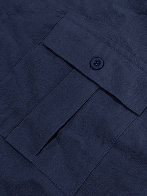 Navy blue button-down shirt detail showing a pocket with a button closure and textured fabric.