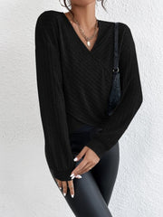 Black ribbed knit cross-front blouse with blouson sleeves and V-neck.
