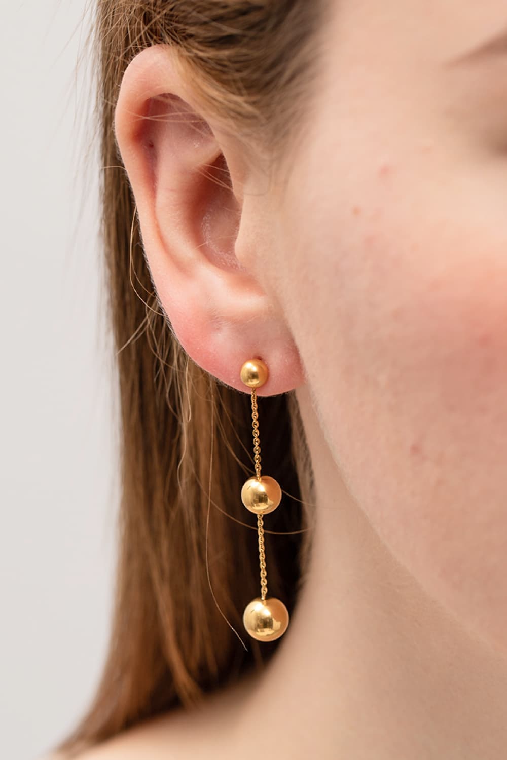 Gold triple orb drop earrings with delicate chains.