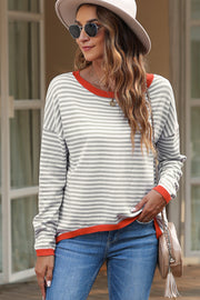 Striped crewneck sweater with contrast orange trim and long sleeves.