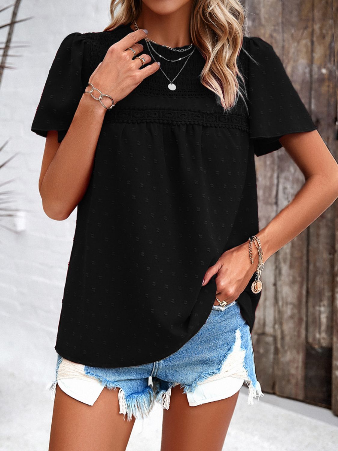 Black dotted swiss smocked bodice flutter sleeve blouse with lace trim detail.