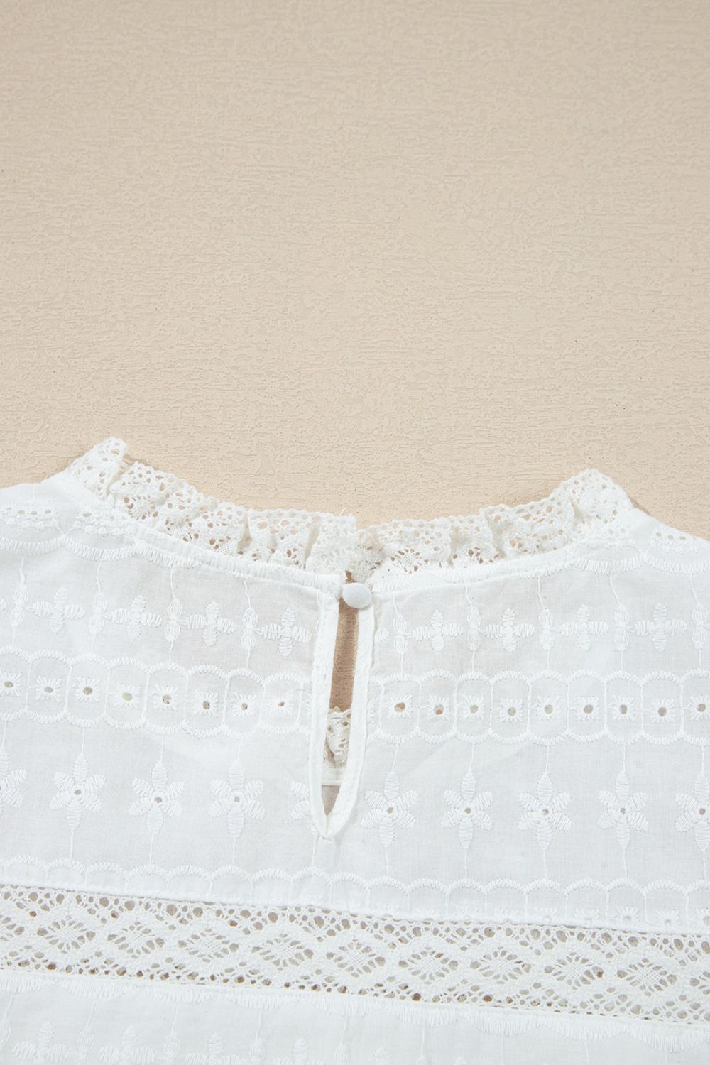 White eyelet yoke blouse with ruffled collar and button back detail.