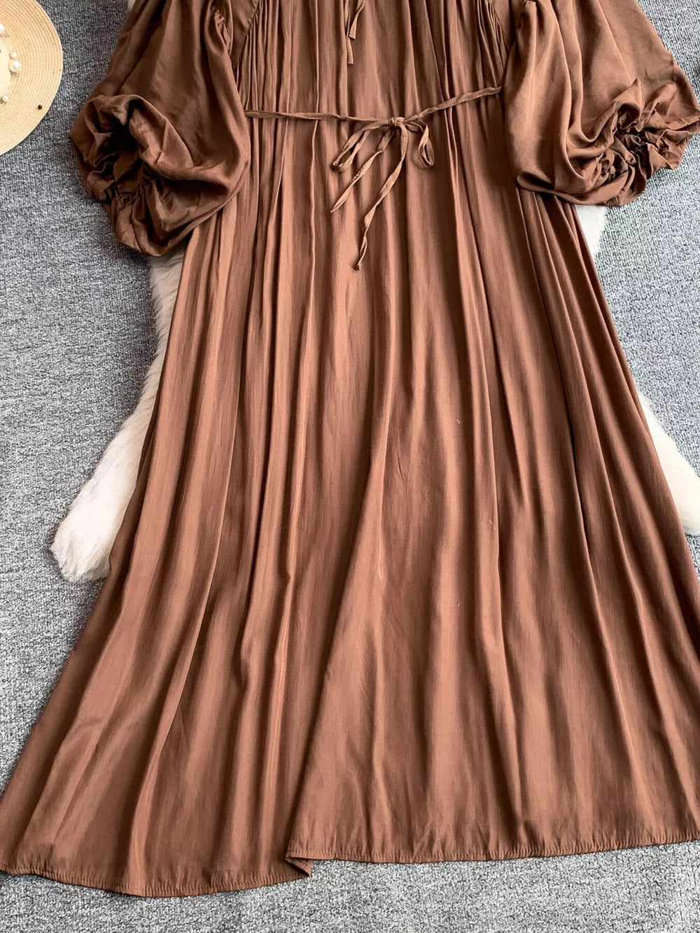 Brown bohemian maxi dress with balloon sleeves, tie waist, and ruffled cuffs.