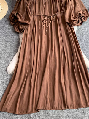 Brown bohemian maxi dress with balloon sleeves, tie waist, and ruffled cuffs.