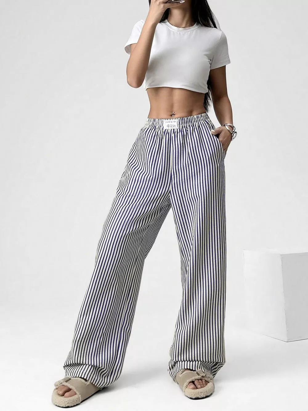 Navy striped high-waisted wide-leg pants with drawstring detail.