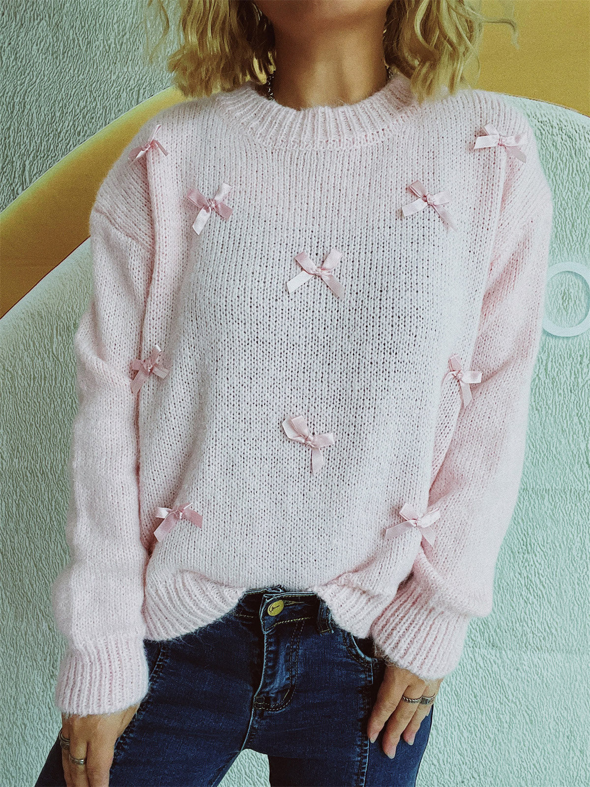 Blush pink knit crewneck sweater with scattered satin bows, crew neck, long sleeves.