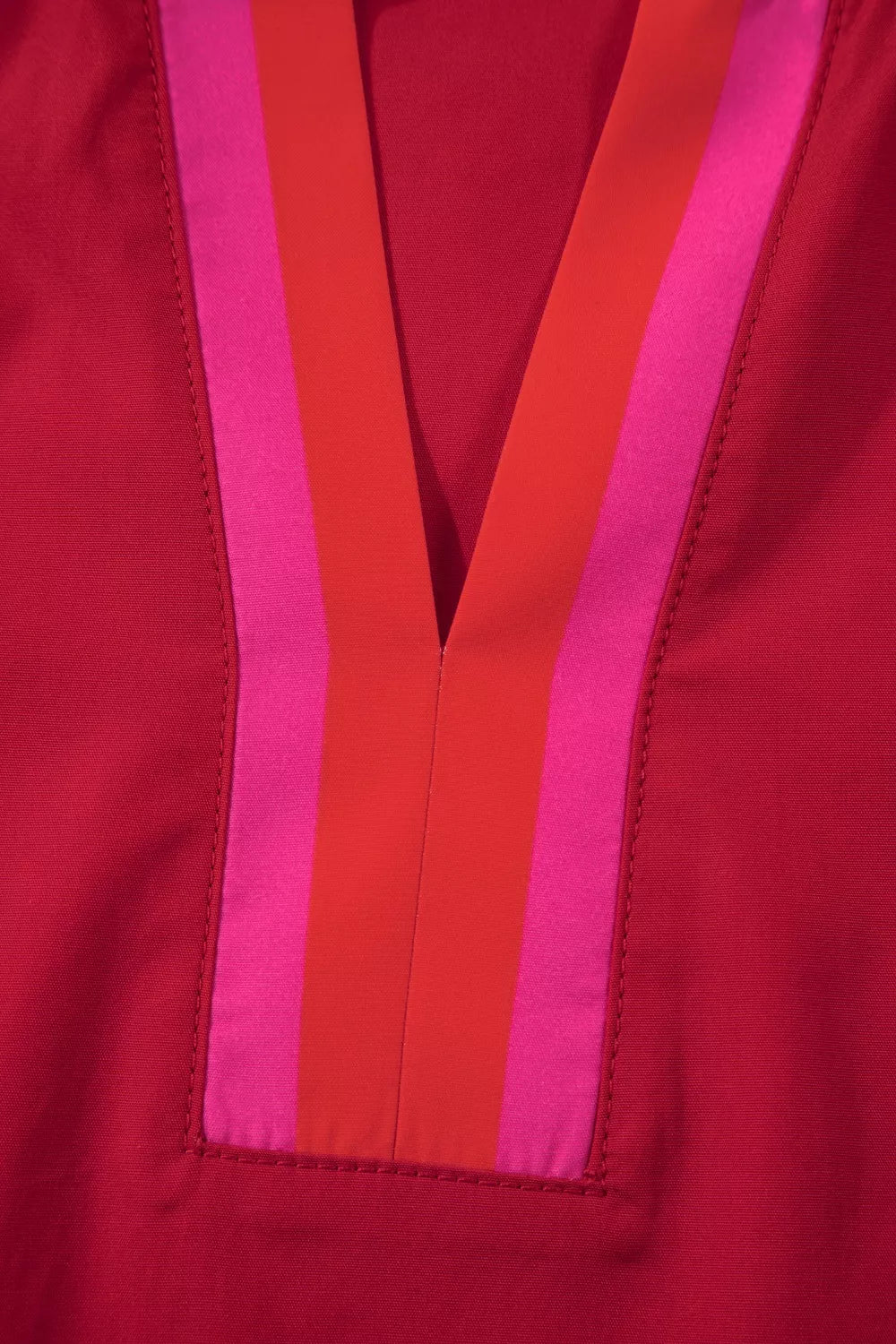 Ruffled maternity blouse in red with pink and orange striped V-neck detail.