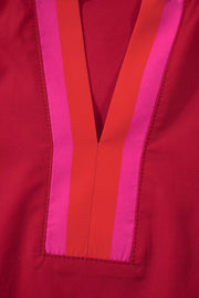 Ruffled maternity blouse in red with pink and orange striped V-neck detail.