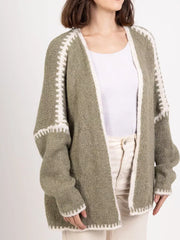 Oversized sage green knit cardigan with white contrast trim and open front.