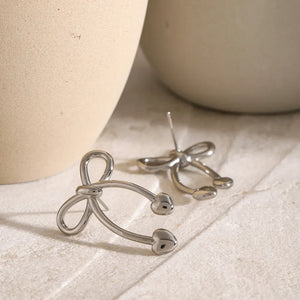 Silver heart-tipped bow drop earrings with a chic, playful design.