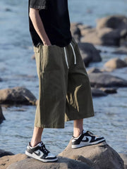 Relaxed fit cropped sweatpants in green with drawstring and pockets.