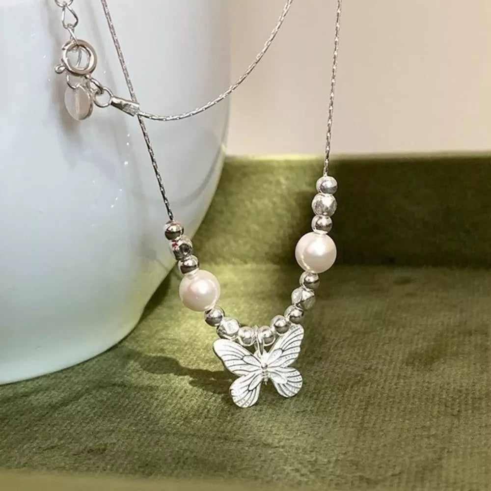 Silver necklace with butterfly charm, pearls, and beaded accents