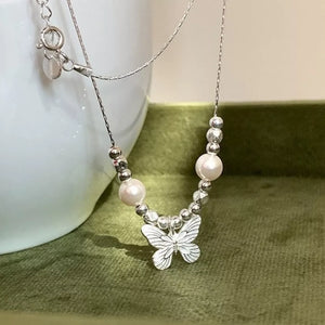 Silver necklace with butterfly charm, pearls, and beaded accents