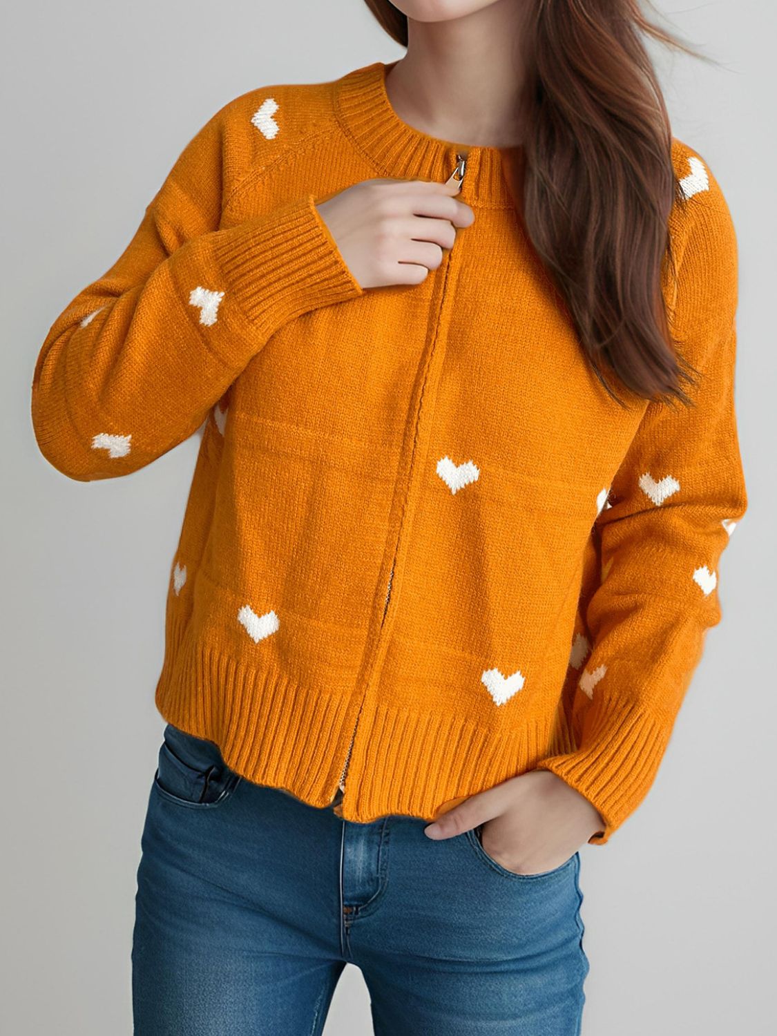 Tangerine zip-through knit cardigan with white heart appliqué and ribbed cuffs.