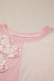 Maternity t-shirt with pink and cream color block, featuring a dimensional applique flower detail.