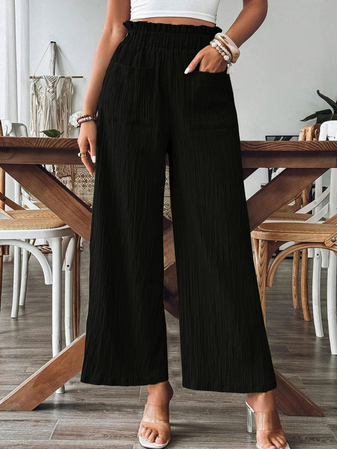 Black textured wide-leg palazzo trousers with ruffled waist and pockets.
